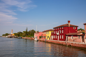 Naklejka premium Scenic view of bright colorful houses on island of Burano in city of Venice, Veneto, Northern Italy, Europe. Cruising around the Venetian Lagoon. Water canal along idyllic riverbank. Summer tourism