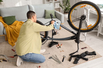 Young man wiping bicycle while repairing at home