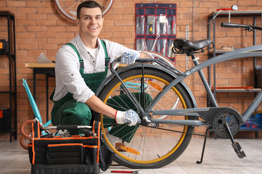 Young mechanic repairing bicycle wheel in workshop