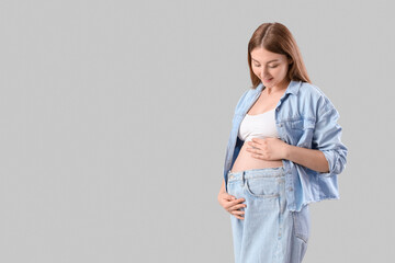 Young pregnant woman on light background