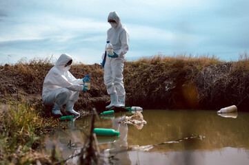 Team of scientists or biologists wears protective clothing to collect water samples from a natural...