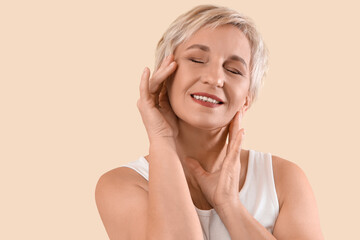 Mature woman with healthy skin smiling on beige background, closeup