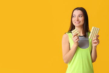 Young woman with white chocolate bar on yellow background