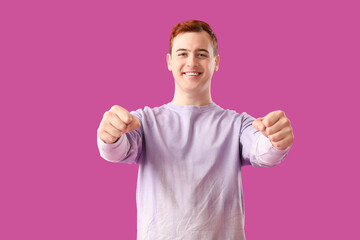 Young man with imaginary steering wheel on purple background