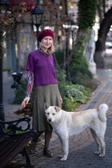 A woman is standing in the street with a stray dog.