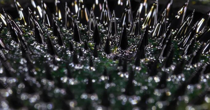 Ferrofluid tinted with colored paints yellow, green. The surface of the black liquid. Abstract background.
