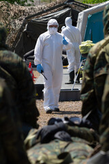 Soldados llevan un herido en camilla a un puesto médico de protección quimica. - obrazy, fototapety, plakaty