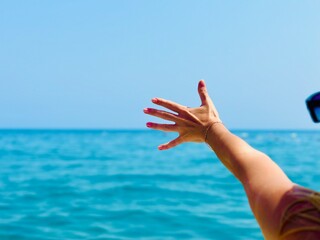 A girl's hand against the background of the blue sea.
