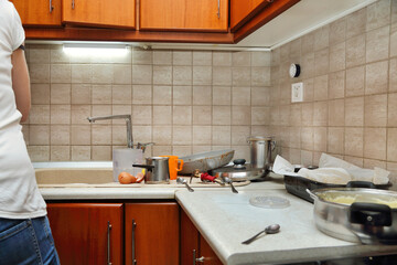 woman in messy kitchen preparing food - 694504288
