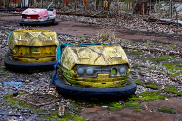 A weathered bumper car stands still amidst wild growth.