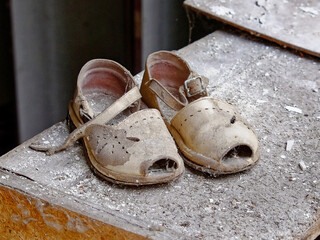 A pair of old, worn-out sandals covered in dust.
