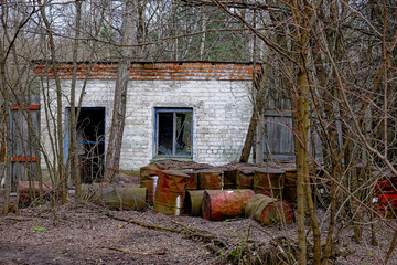 The image shows an old, possibly abandoned building with white brick walls and a deteriorating...