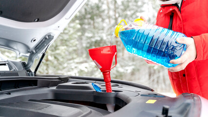 The driver pours winter glass cleaner into the car