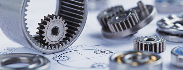 Close up metal gears and bearings. Background with drawings of the mechanism. Industrial mechanism.