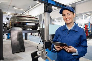 Servicewoman with digital tablet on the background of the car in the car service.