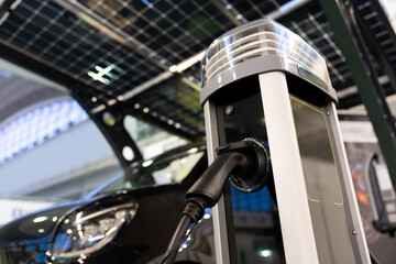 Electric car is charged from a charging station that takes energy from solar panels. Close up..
