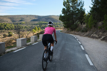 Fit female cyclist riding a gravel bike with a view of the Spanish mountains. Athlete wearing...