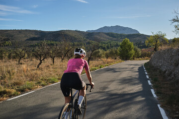 Fit female cyclist riding a gravel bike with a view of the Spanish mountains. Athlete wearing...