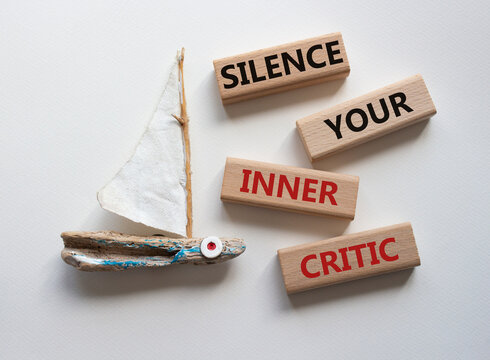 Silence your inner critic symbol. Wooden blocks with words Silence your inner critic. Beautiful white background with boat. Business and Silence your inner critic concept. Copy space