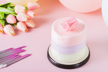 Cotton candy cake, flowers, candles and balloons for party on table