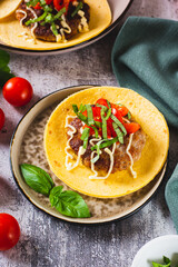 Smash Burger Tacos with beef patty, tomatoes and basil on a plate vertical view