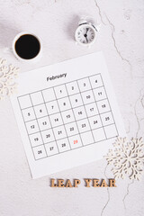 Leap year concept, calendar, coffee, alarm clock and text on light top and vertical view