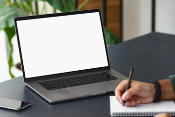 Fototapeta na wymiar Open laptop with blank screen on office desktop. Businessman or student writing notepad while sitting at desk with computer