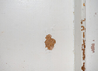 Part of an old door. White paint is coming off the wood. Surface with peeling paint.