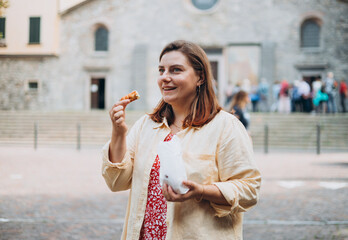 Happy woman holding Sicilian cannolo tube pastry filled with cream. Travel, Italy and holidays...