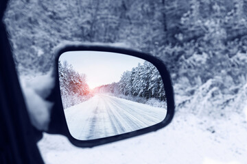The winter road is reflected in the rear mirror of the car. Close-up
