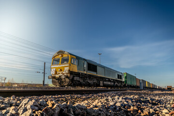 A UK freight train with locomotive and wagons transporting shipping container boxes