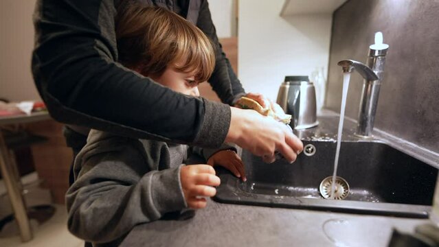 Mother and child washing dishes in kitchen sink, family lifestyle scene of little boy helping mom with domestic chores
