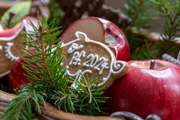 Christmas decoration made of red apples, coniferous twigs and gingerbread with the inscription PF 2024.