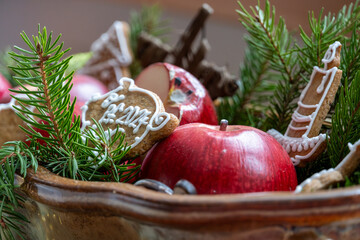 Christmas decoration made of red apples, coniferous twigs and gingerbread with the inscription PF...