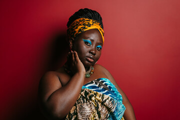 Gorgeous plus size African woman with beautiful make-up wearing traditional attire standing 