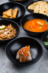 Spring rolls with chicken, rice noodle pad thai with squid, Tom yum soup with chicken, Naan flatbread and omelette on a table.