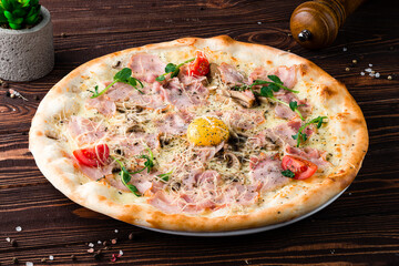 Pizza with raw yolk, bacon, mushrooms, cheese, tomatoes, spices and microgreens, Italian lunch.