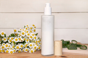 Natural handmade cream into a glass bottle on a white wooden background with aloe vera leaf and...