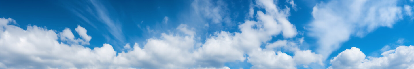 Obraz premium Panoramic view of a blue sky with white fluffy clouds as the backdrop.
