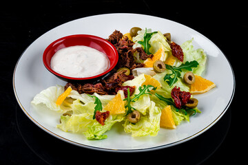 Fried meat with onions and a salad of oranges, sun-dried tomatoes, arugula, olives, lettuce and...