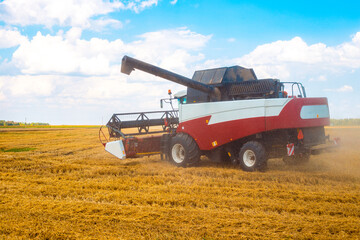 A combine harvester stands on a field after harvesting wheat on a sunny autumn day. Harvesting,...