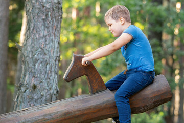 Happy cute little boy lift up with Outdoor seesaw or wooden swing on a playground