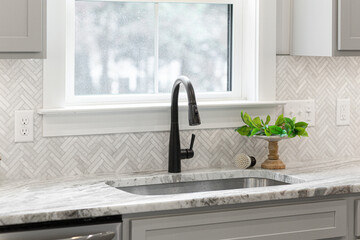 Minimal Contemporary Kitchen Sink Area with Green Potted Plant and Stylish Herringbone Backsplash...