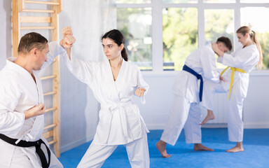 Karate training - man and woman in kimono sparring in the gym