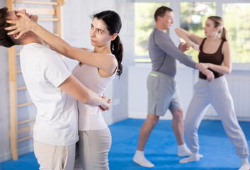 Aggressive young woman practicing self-defense techniques in pairs with guy during workout session