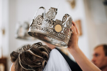 The priest holds a silver crown over the head of the bride in the temple, conducting the wedding...