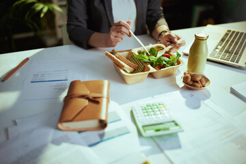 Modern business owner woman in green office eating salad