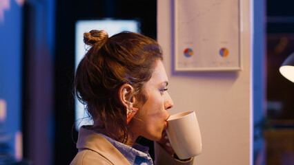 Frustrated person sitting in office late at night working on marketing analytics with data on...