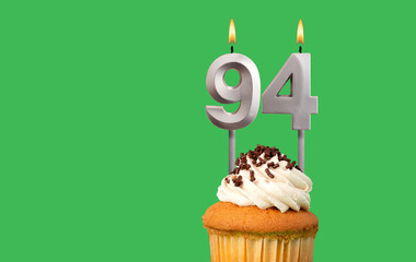 Birthday with number 94 candle and cupcake - Anniversary card on green color background