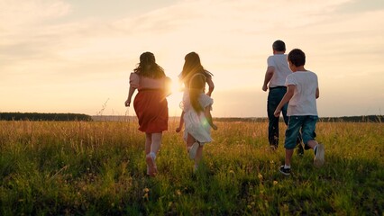 Happy children with father and mother spend time on grass field at sunset. Happy family. Children...